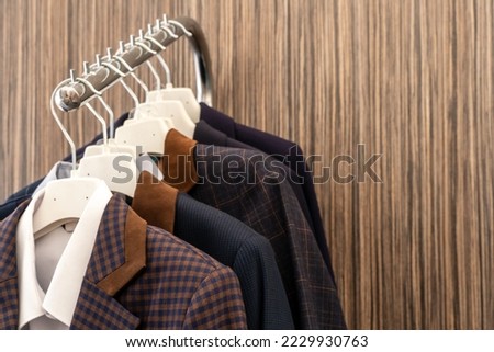 New business men's suits are hanging on hangers in the store. Modern fashionable clothes. A luxury store with mens clothing. Designer business suits Royalty-Free Stock Photo #2229930763