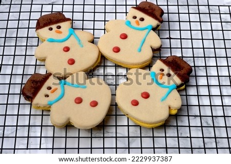 Butter cookies in the shape of a snowman on a black grid with a white background, Christmas background, Christmas cookies