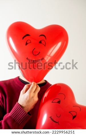 man with two heart-shaped balloons with one-sided drawing, valentine's day gift card, vertical