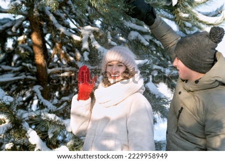 Laughing young woman with red lips happy smiling under falling snow. Guy have a fun with his girlfriend. Winter walk.