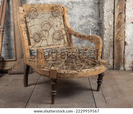 Defective old broken armchair on the old floor next to other vintage things