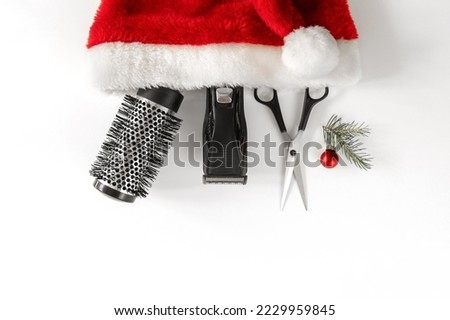 Christmas composition. Hairdressing tools in a Santa Claus hat on a white background. Template for a postcard or information about a hair salon. Flat lay, copy space