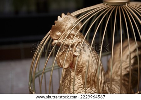 Golden Cage. Decorative Golden Rooster with a Scallop in a Cage Royalty-Free Stock Photo #2229964567