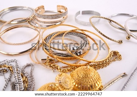 A large selection of costume jewellery on a white surface. To include rings, necklaces, chains, bracelets, bangles and cufflinks.