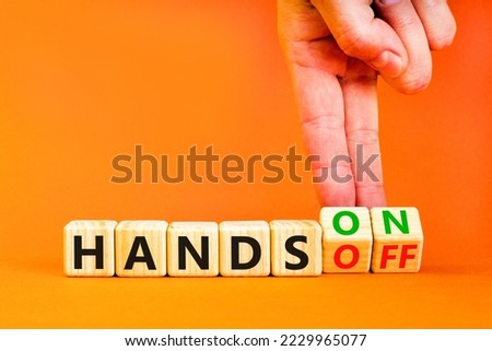Hands on or off symbol. Concept words Hands on Hands off on wooden cubes. Businessman hand. Beautiful orange table orange background. Business hands on or off concept. Copy space.