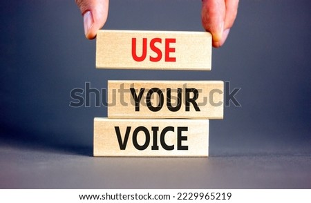 Use your voice symbol. Concept words Use your voice on wooden blocks on a beautiful grey table grey background. Businessman hand. Business and use your voice concept. Copy space.