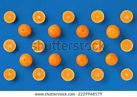 Fruit pattern of fresh orange tangerine or mandarin over blue background. Flat lay, top view. Pop art design, creative summer concept. Citrus in minimal style.