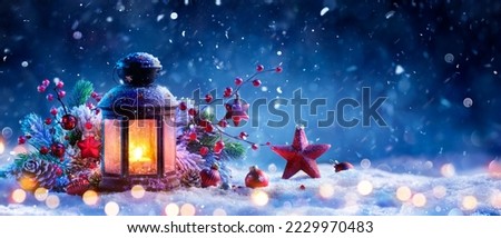 Christmas Lantern On Snow At Eve Night With Decorations And Ornaments - Candle Light With Snowfall And Abstract Defocused Lights 