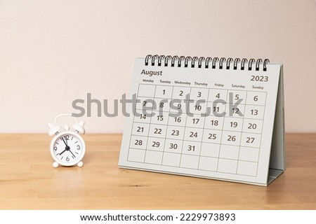 August 2023 calendar and small alarm clock on a wooden table Royalty-Free Stock Photo #2229973893