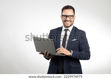 Business man portrait on white studio background, using laptop and smiling