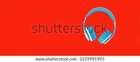 Close up of blue headphones on colorful red background, top view, blank copy space for advertising text
