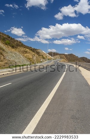 Curvy road rising between the mountains. Sunny day with clouds. Travel and feeling of freedom.