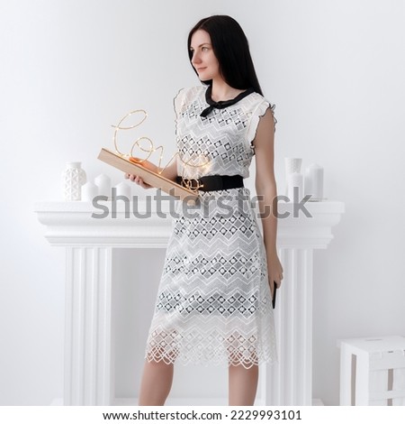 Attractive girl in a white lace dress holds a decorative sign in her hands on valentine's day. Sign with the inscription "Love".