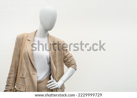 A female mannequin in a suit on a shop window. Sale of modern fashionable clothes. Bright youth clothing wholesale and retail. Royalty-Free Stock Photo #2229999729