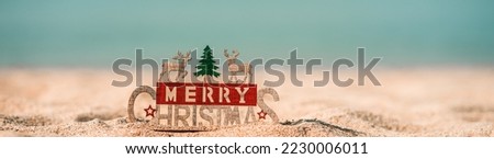 Merry Christmas word in wooden on the beach of tidewater green tone background, wide banner, Christmas banner, happy concept, copy space, soft focus