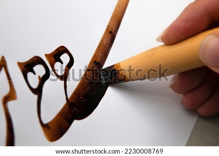 A calligrapher writing with pen and ink. man hands writing arabic calligraphy with ink. Arabic and Persian calligraphy. Writing Nastaliq calligraphy. Calligraphy training. Close-up of Arabic reed pen Royalty-Free Stock Photo #2230008769