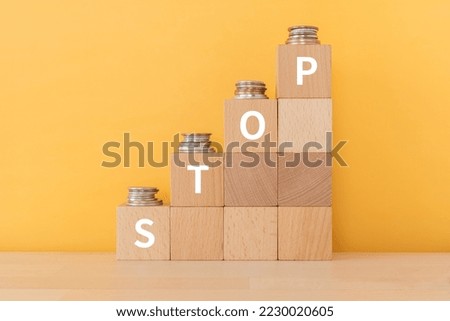Wooden blocks with "STOP" text of concept and coins.