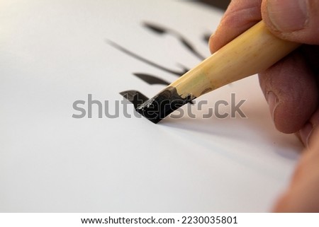 A calligrapher writing with pen and ink. man hands writing arabic calligraphy with ink. Arabic and Persian calligraphy. Writing Nastaliq calligraphy. Calligraphy training. Close-up of Arabic reed pen Royalty-Free Stock Photo #2230035801