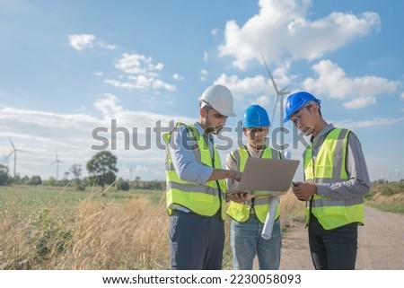 Asian engineers working in fieldwork outdoor. Workers walking and inspect construction and machine around project site. Wind turbine electrical of clean resource enerdy and environment sustainable.