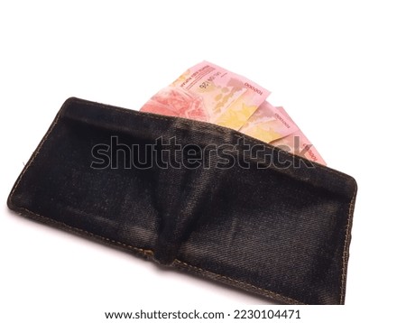 One hundred thousand rupiah money is in a black wallet, isolated background.