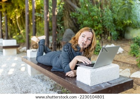 A beautiful freelancer woman works at the park using a computer.