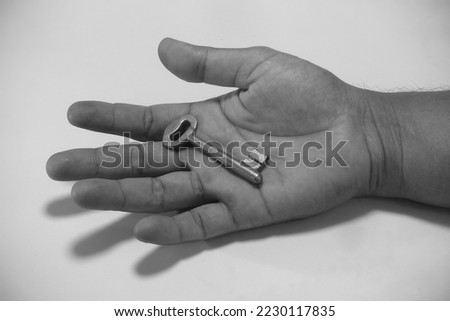 hand holding metal key isolated in white background, studio shoot day time, black and white photography, illustration key of success.
