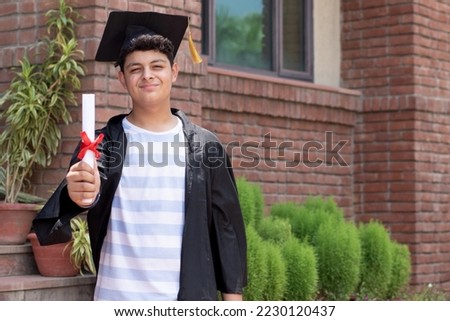 Young indian graduated boy holding his graduation degree convocation ceremony. multiracial student graduate posing. Royalty-Free Stock Photo #2230120437
