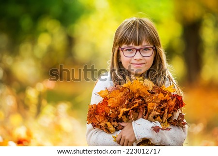 Portrait of a young pretty girl who was cheerfully playing with autumn maple leaves.