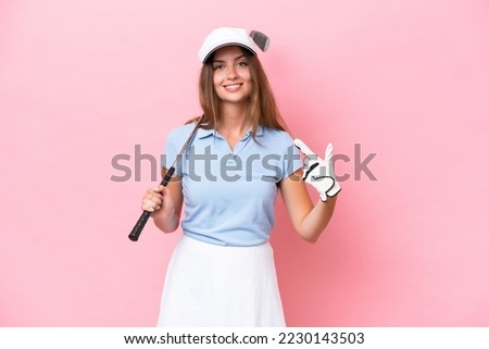 Young golfer player man isolated on pink background giving a thumbs up gesture