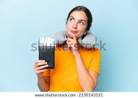 Young beautiful woman with Inflatable travel Pillow isolated on blue background and looking up