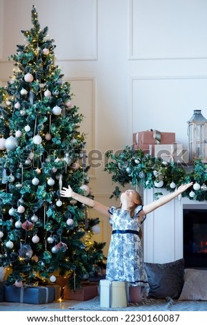 a girl dressed in a dress sitting in a room with Christmas decoration