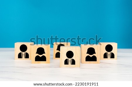 Wooden cubes with people icons over a marble table with a blue background. Teamwork and unity concept. Space for text. Close-up photo