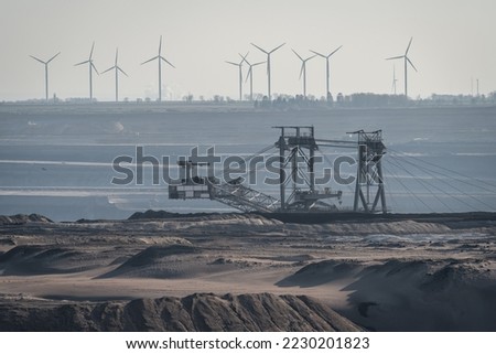 View of surface mine in Germany, heavy machinery in lignite mine and wind turbines in the background Royalty-Free Stock Photo #2230201823