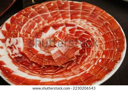 Plate with Iberian cut ham. Spanish jamon iberico (ham). Selective focus point Royalty-Free Stock Photo #2230206543