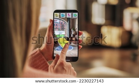Decorating Apartment: Woman Holding Smartphone, using Augmented Reality Interior Design Software Chooses 3D Furniture for Home. Pick a Stylish Chair for the Living Room. Over Shoulder Close-up Screen