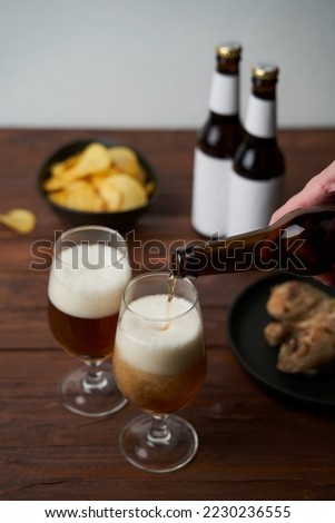 Two glasses with beer, snacks and bottles