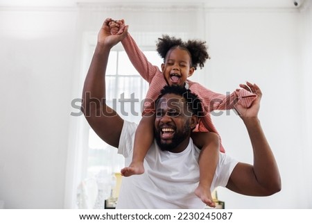 enjoy happy love black family african american father carrying daughter little african girl child smiling in the white living room at home. Happy black African American father day concept. Royalty-Free Stock Photo #2230245087