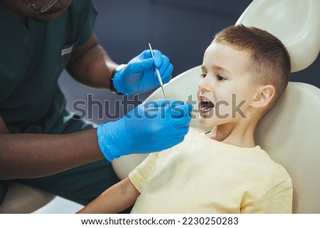 Dentists with a patient during a dental intervention to boy. Dentist Concept. Little boy at the dentist. Young dentist is treating cute little boy's teeth. Little boy at regular dental check-up Royalty-Free Stock Photo #2230250283