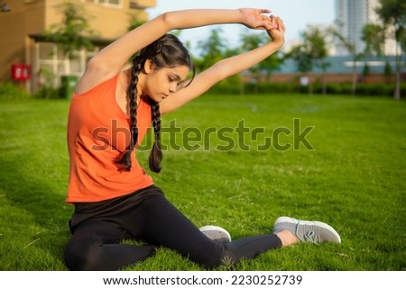 Outdoor image of Asian, Indian young woman doing exercises and yoga asana in outdoor at the park.