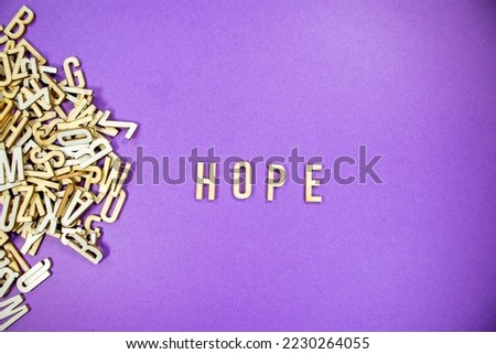 purple background with a pile of wooden capital letters spilling into words - HOPE