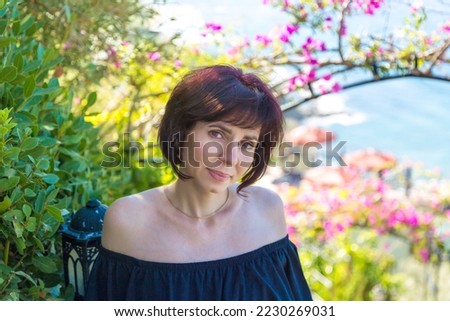 Portrait of a brunette woman 40-44 years old in a black dress with bare shoulders. Royalty-Free Stock Photo #2230269031
