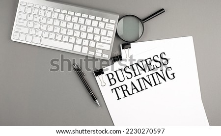 BUSINESS TRAINING text on a paper with keyboard on grey background