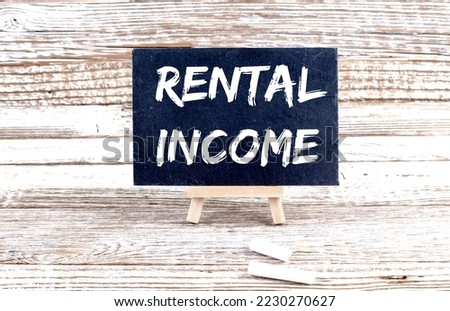 RENTAL INCOME text on Miniature chalkboard on wooden background