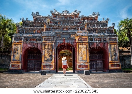 Young woman touring the interior of the ancient imperial city of Hue, Vietnam. Ancient stone gate of the imperial city of Hue, Vietnam. Happy tourist in Vietnam. Old gate of the imperial city of Hue Royalty-Free Stock Photo #2230275545