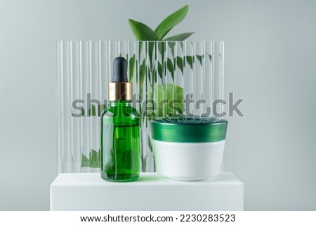 Cosmetics SPA branding mock-up. Green glass cosmetic bottles and jars on on white podium on gray background with copy space. Natural organic beauty product concept, Minimalism style