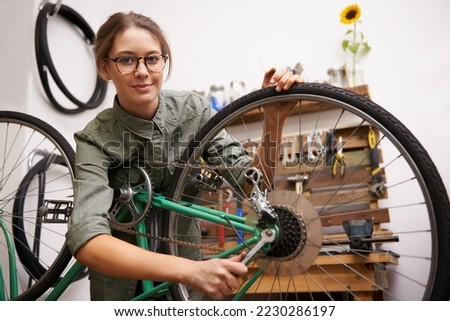 Girls can fix things too. Shot of a young woman looking at the camera while fixing a bicycle. Royalty-Free Stock Photo #2230286197