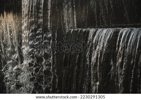 A waterfall flowing at park Wall of water A beautiful view of the falling water cascade city fountain close-up pouring Royalty-Free Stock Photo #2230291305