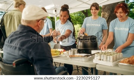 Team of Volunteers Helping in a Local Community Food Bank, Handing Out Free Food to Low-Income People in a Park on a Sunny Day. Man with Disabilities Using Wheelchair is Thankful for Charity Meal. Royalty-Free Stock Photo #2230295127