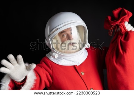 Flying Santa Claus astronaut in a helmet with a bag of gifts. Space gifts from Santa. Winter travel christmas concept. Royalty-Free Stock Photo #2230300523