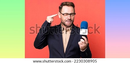 middle age man feeling confused and puzzled, showing you are insane. journalist and a microphone concept